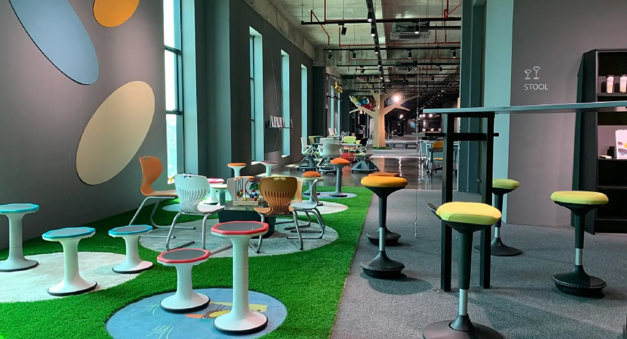 A breakout area with coloured stools and chairs on artificial grass
