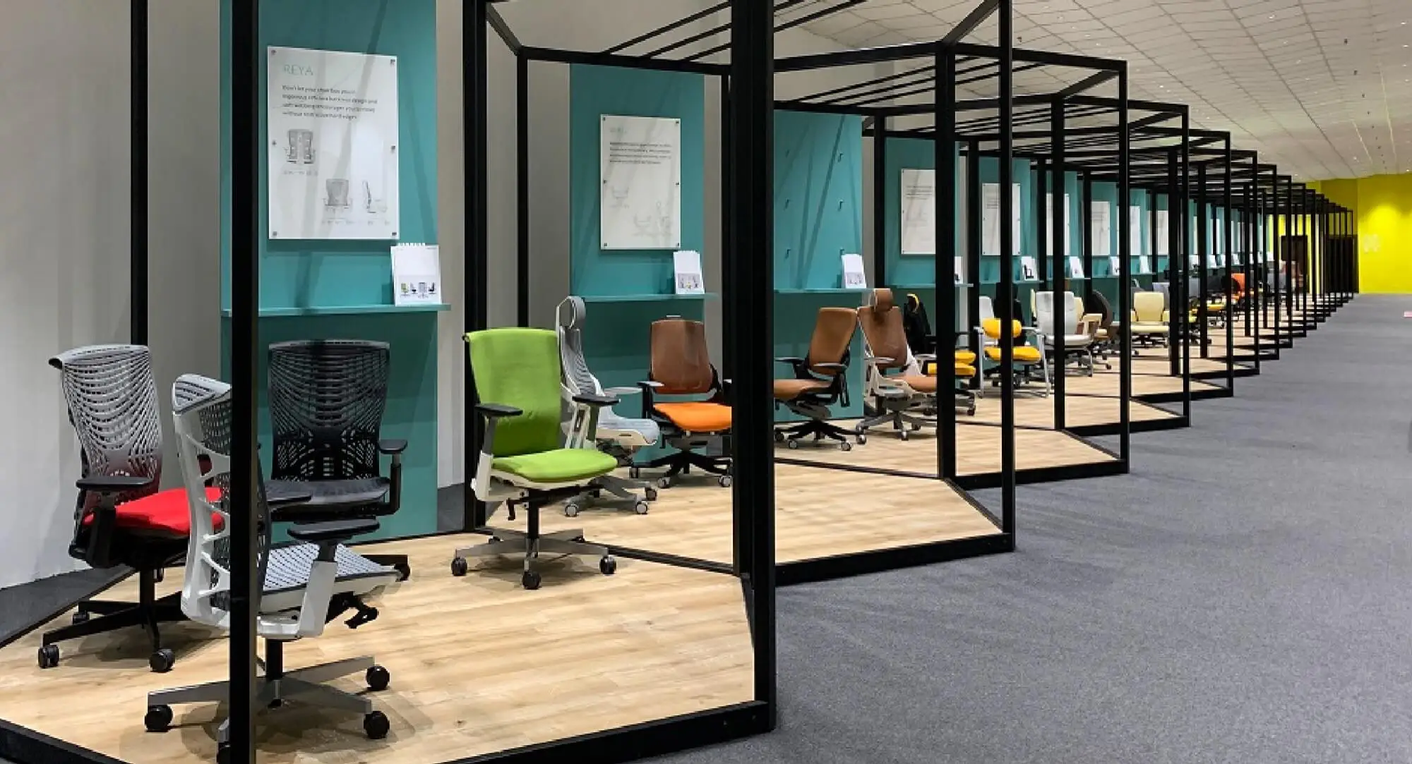 Rows of glass-framed bays with mesh task chairs in black, green and orange